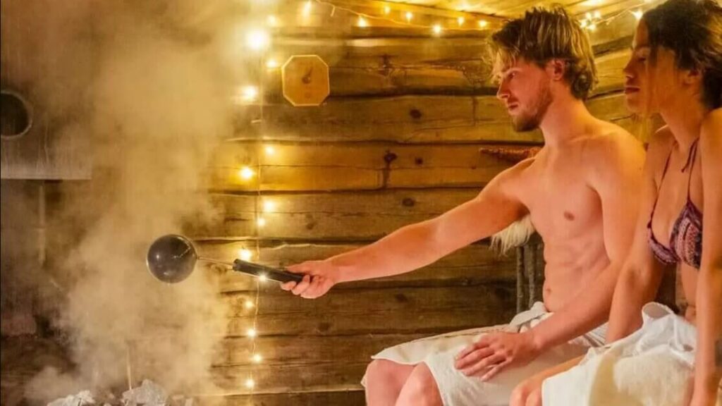 A man and woman enjoying an authentic Finnish sauna experience, pouring water on hot stones to create steam in a rustic wooden cabin with warm decorative lights.