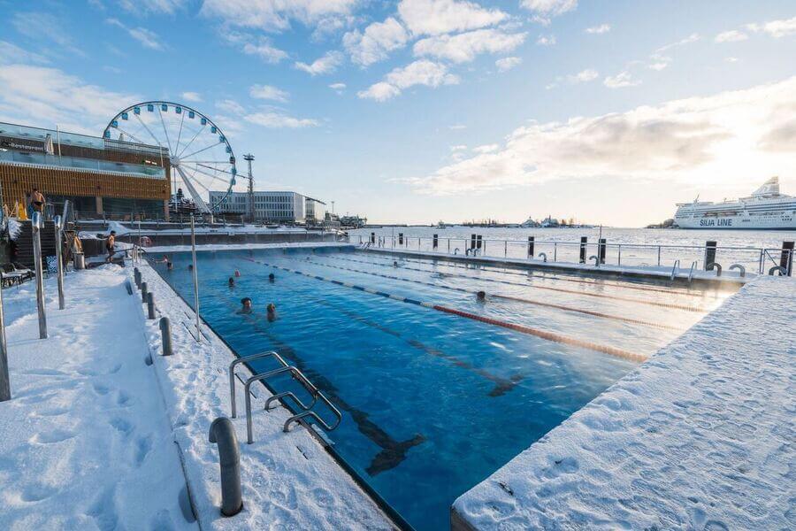 Outdoor swimming at Allas Sea Pool in Helsinki city center during winter, with a view of the Baltic Sea and SkyWheel.
