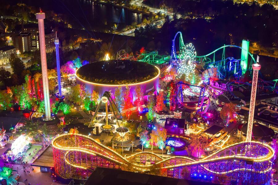 Vibrant night view of Linnanmäki Amusement Park in Helsinki, featuring glowing roller coasters and colorful lights for family fun.