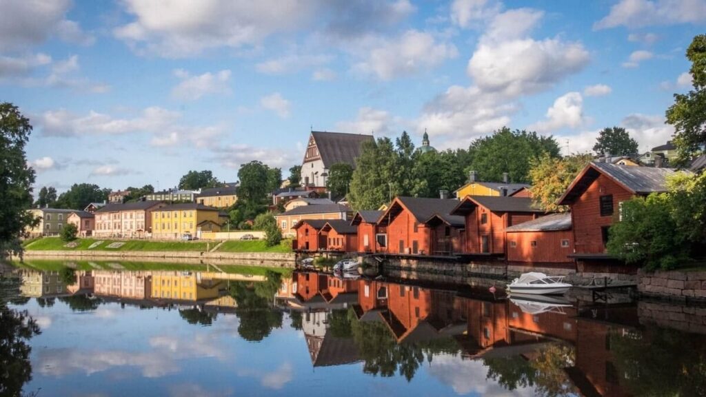 Traditional red wooden warehouses reflected in the river at Porvoo old town, a popular summer day trip destination from Helsinki, Finland.